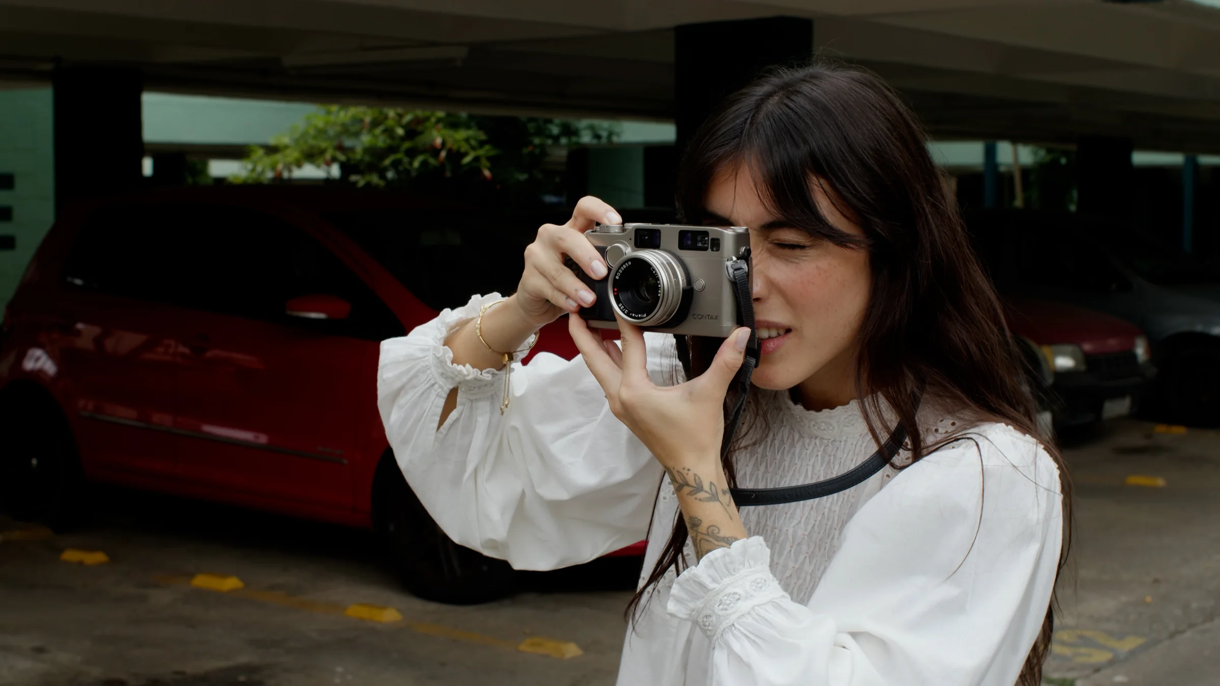 Maju fotografando com uma câmera analógica em um estacionamento