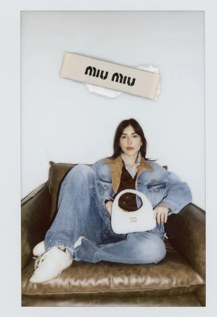 Foto instantânea da Maju sentada em um sofá de couro, com roupa jeans